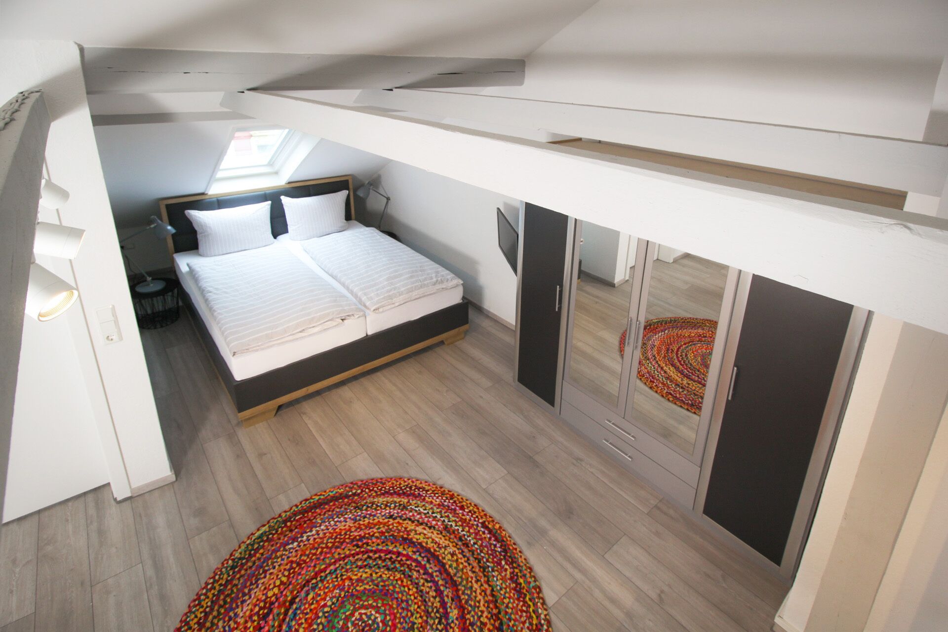 A bedroom with a bed, a desk, and a wardrobe.