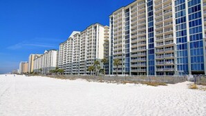 A beachfront hotel with multiple floors, balconies, and a sandy beach in the foreground. - 3BD/3BA Tower 3 Corner Renovated Condo! Comes with beach chairs and umbrella! (Panama City Beach)