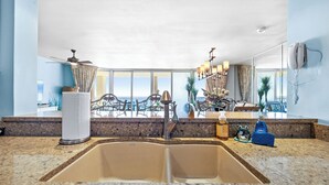 A modern kitchen with a granite countertop, a double sink, and a view of the ocean. - 3BD/3BA Tower 3 Corner Renovated Condo! Comes with beach chairs and umbrella! (Panama City Beach)