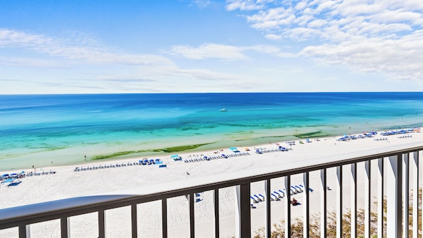 A beach view from a balcony with a railing, clear blue sky, and turquoise sea. - 3BD/3BA Tower 3 Corner Renovated Condo! Comes with beach chairs and umbrella! (Panama City Beach)