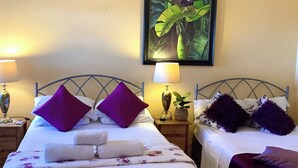 A hotel room with two beds, each with a headboard, a nightstand with a lamp, and a framed picture on the wall. - A Touch Of Class To Your Stay-Our Iconic Egg Chair. (Basseterre)