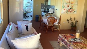 A cozy living room with a sofa, a dining table set for two, a hanging chair, and a kitchen area with cabinets and appliances. - A Touch Of Class To Your Stay-Our Iconic Egg Chair. (Basseterre)