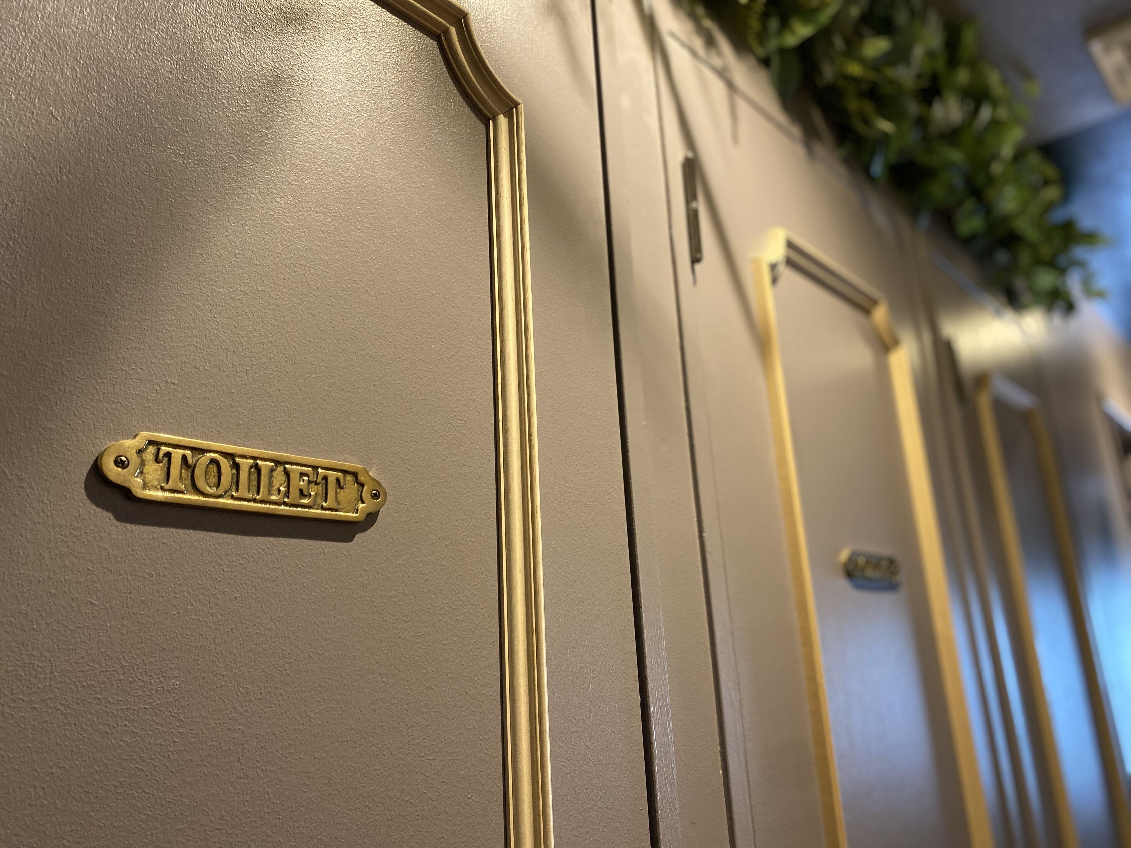 A close-up of a gold-colored door with a brass nameplate reading "TOILET".