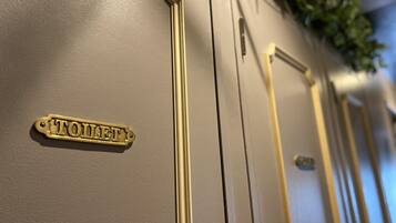 A close-up of a gold-colored door with a brass nameplate reading "TOILET".