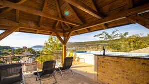 Une pergola en bois, avec une piscine et des chaises, donnant sur un paysage pittoresque.