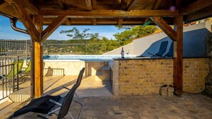 Un espace extérieur abrité comprenant une piscine, des chaises longues et un mur en pierre.
