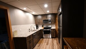 Una cocina moderna con armarios de madera, electrodomésticos de acero inoxidable y salpicadero de azulejos.