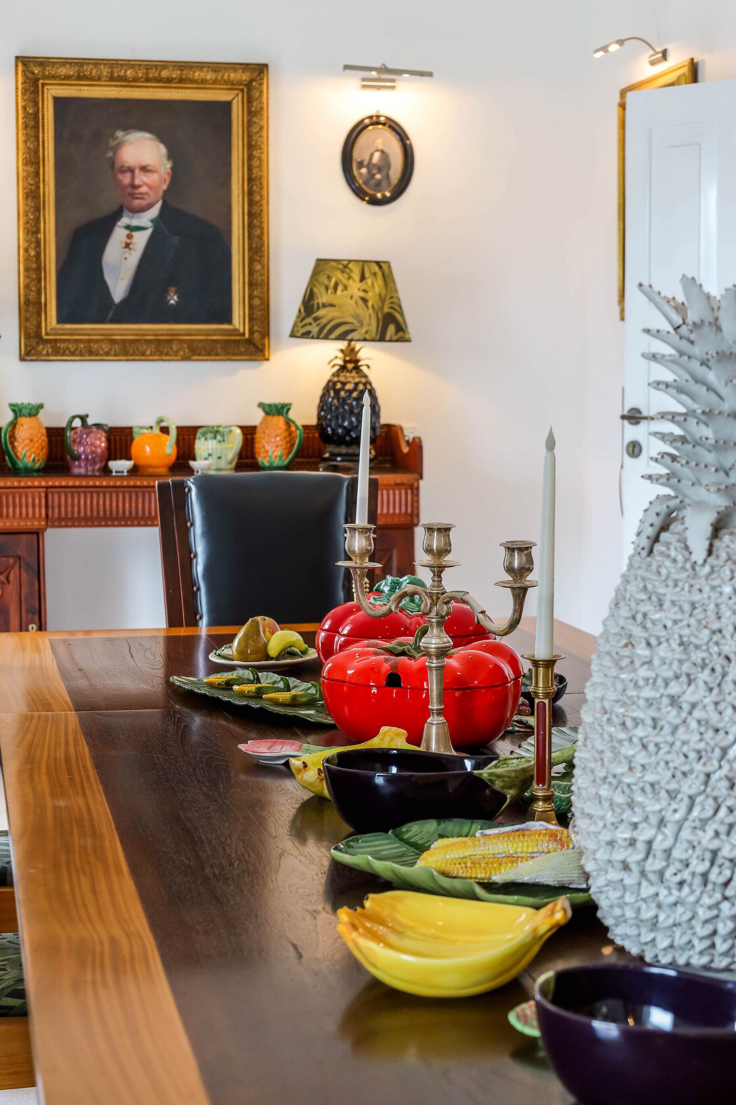 Een eettafel met verschillende gerechten, een ingelijst portret en een decoratieve lamp.