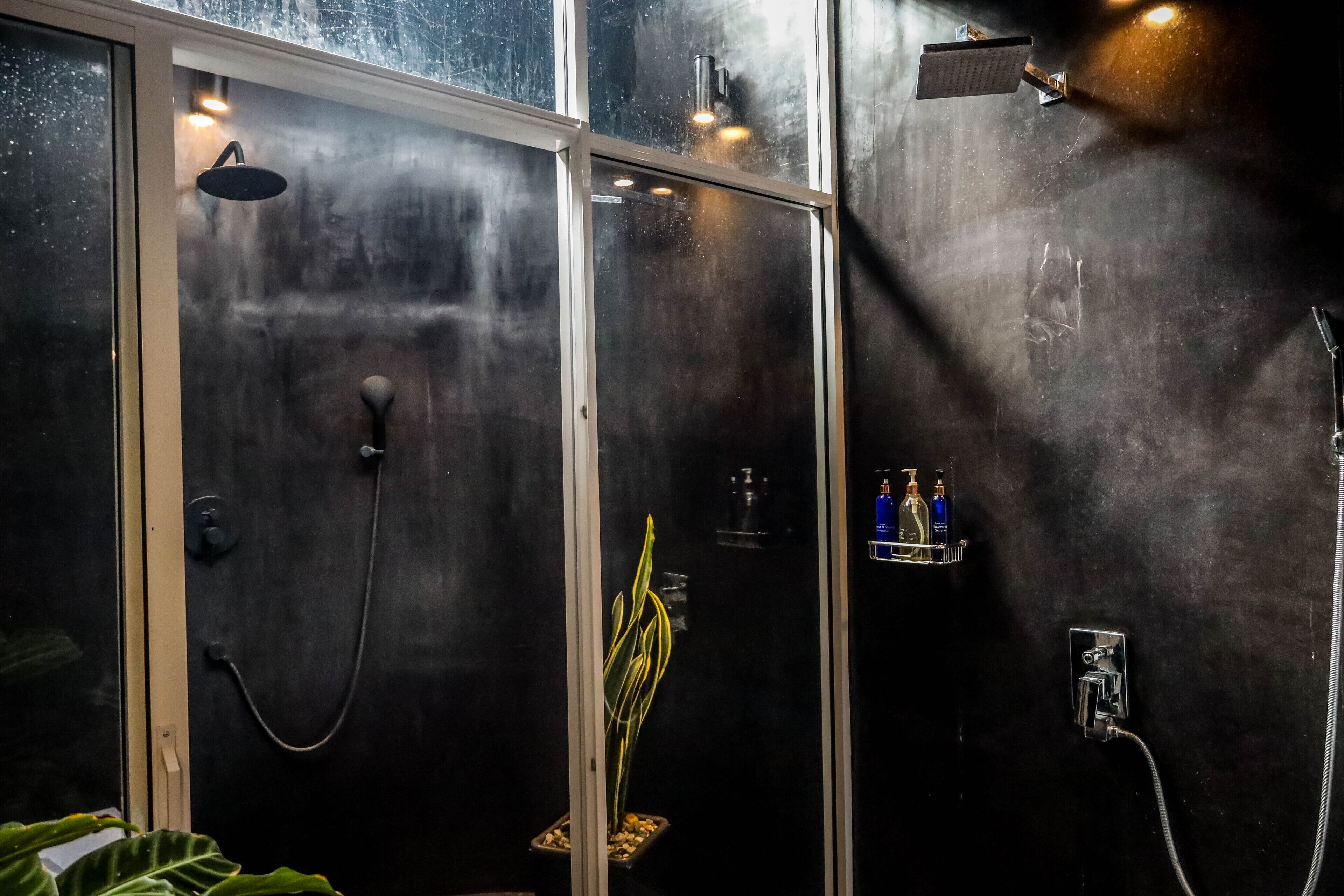 A modern bathroom with a glass shower enclosure, a handheld showerhead, and a wall-mounted faucet.