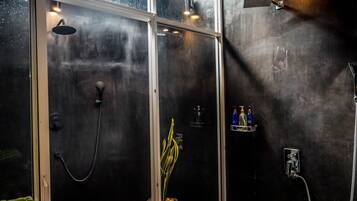 A modern bathroom with a glass shower enclosure, a handheld showerhead, and a wall-mounted faucet.