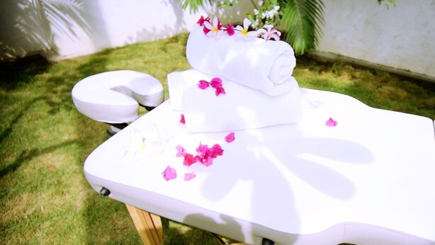 A massage table with a towel and flowers, set on a wooden stand in a grassy area. - The Flame Tree Estate & Hotel (Galagedara)