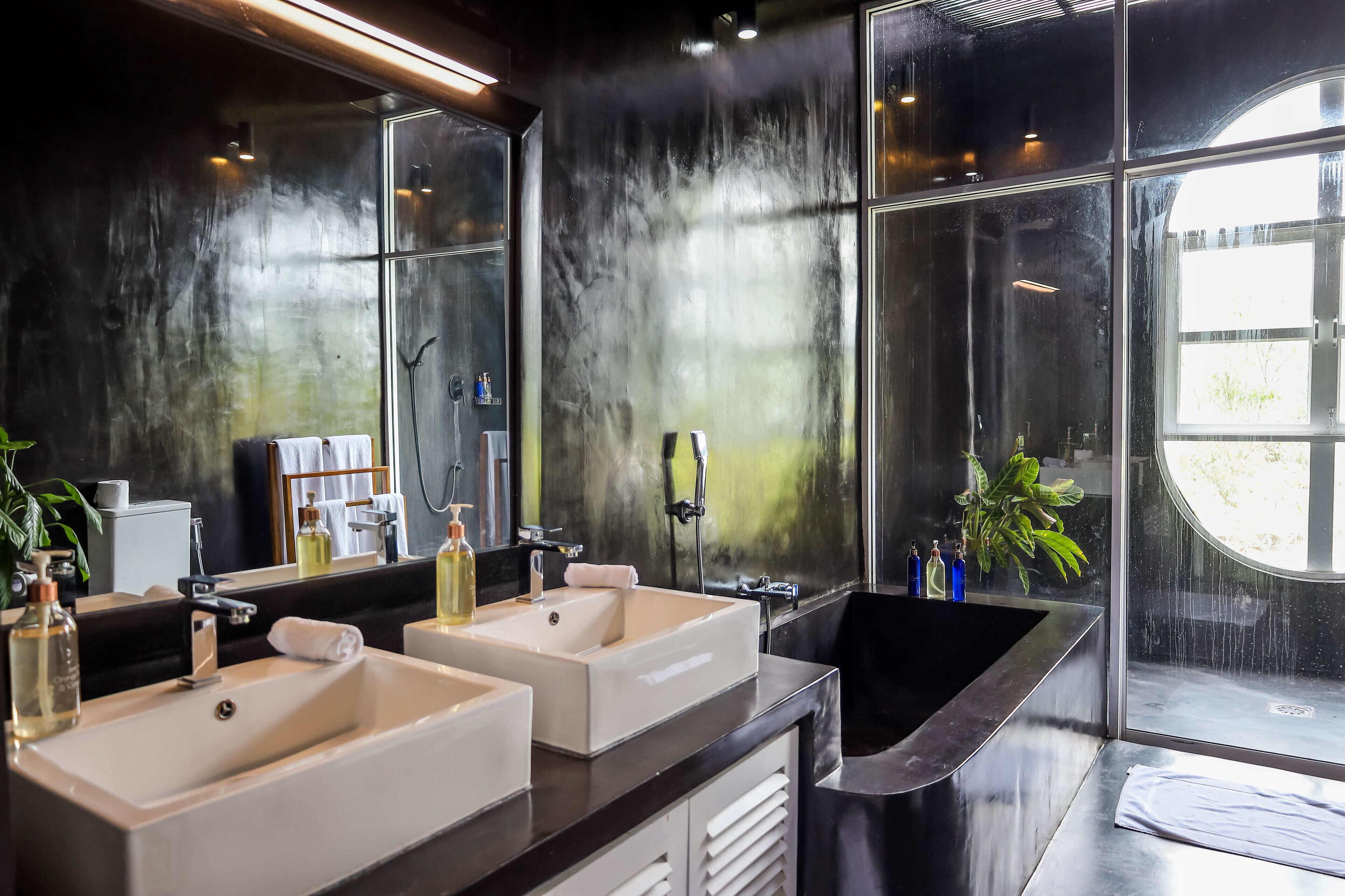 A modern bathroom with two sinks, a large bathtub, and a large mirror.