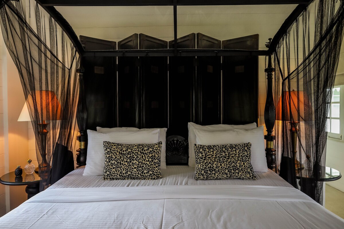 A bed with white linens, two leopard print pillows, and a black headboard.