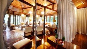 A spacious room with wooden flooring, multiple seating areas, and large windows offering natural light. - The Flame Tree Estate & Hotel (Galagedara)