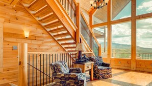 Un interior de madera con escalera, ventanas amplias y mobiliario estampado.