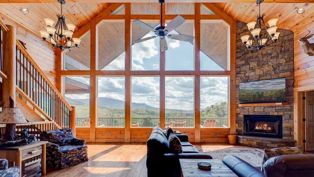 Un salón espacioso con un ventanal grande, una chimenea y un ventilador de techo.