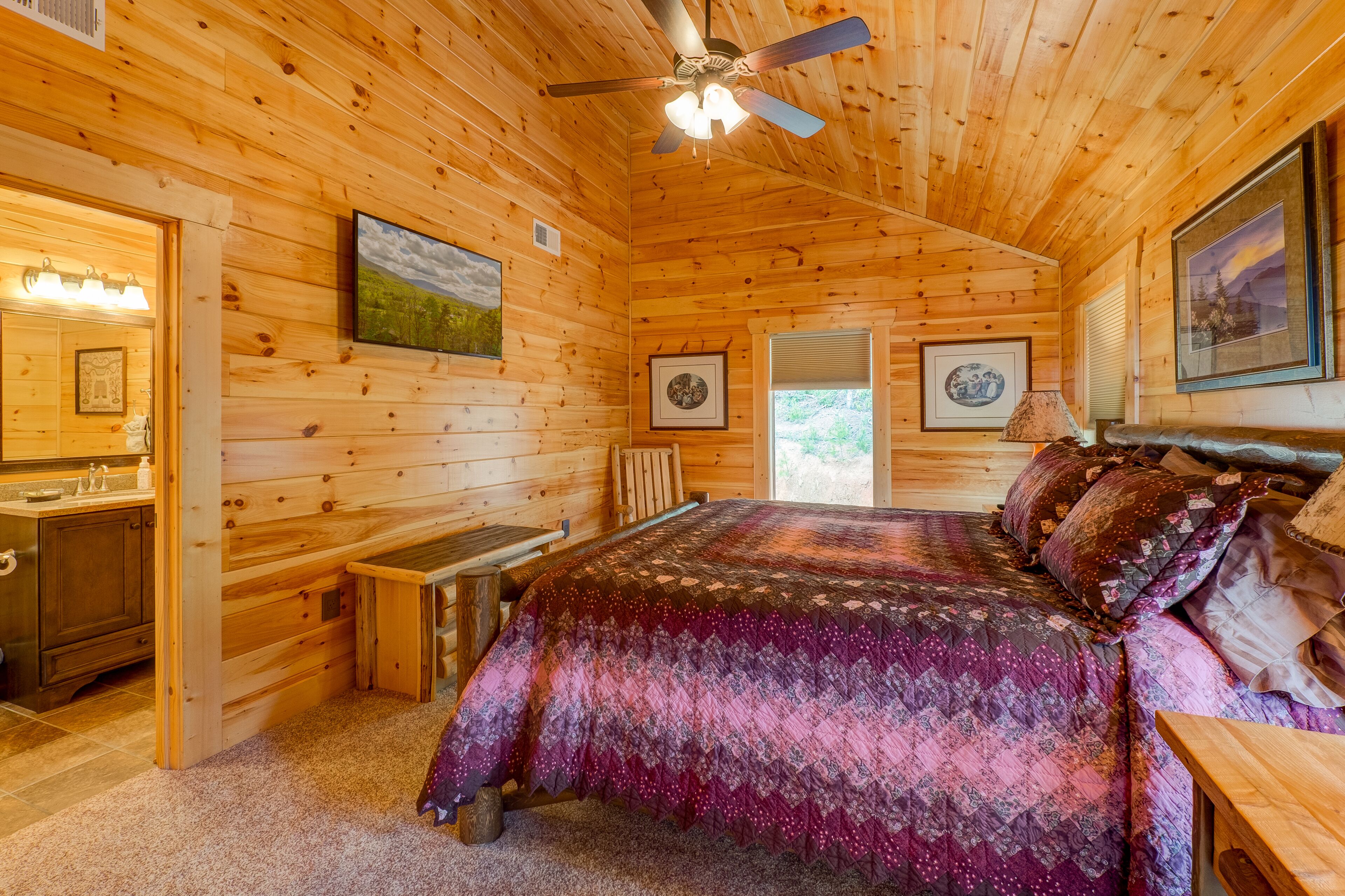 A wooden cabin interior with a bed, a desk, and a bathroom.