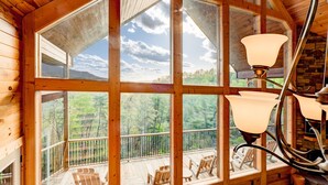 Una cabaña de madera con ventanas amplias, un balcón y una chimenea de piedra.