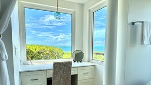 A bathroom with a large window, a chair, a mirror, and a towel rack.