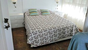 A bedroom with a bed, two bedside tables, a nightstand, a wall-mounted lamp, and a window with blinds. - Apartment for 4 people terrace sea view Cambrils beach 230m (Cambrils)