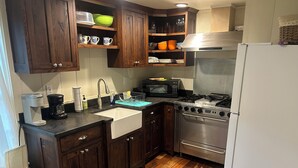 A kitchen with wooden cabinets, a stainless steel stove, a microwave, and a sink. - Historical Farm Cottage Retreat near Clemson (Westminster)