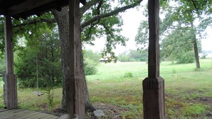 A wooden deck with a rustic wooden railing, a bucket, and a swing hanging from a tree. - Historical Farm Cottage Retreat near Clemson (Westminster)