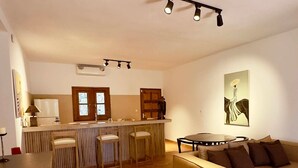 Un grand espace de vie comprenant un canapé, une table à manger et un coin cuisine avec un réfrigérateur et des placards.