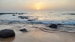 Une plage avec des rochers et des vagues au coucher du soleil.