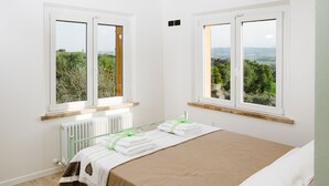Una camera da letto con un letto, due finestre che danno su del verde, un termosifone e un pavimento in legno.