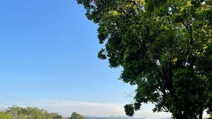 Area piscina con vista su montagne lontane, circondata da vegetazione rigogliosa e un cielo sereno.