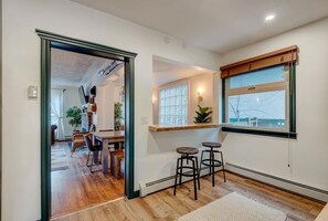 A modern kitchen with a wooden countertop, two bar stools, and a window with a view. - Banff Mountain Home- The Real Rockies Experience (Banff)