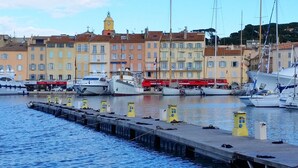 Un port de plaisance avec des bateaux amarrés, une jetée dotée de bornes d’amarrage et, au fond, des bâtiments avec des balcons.