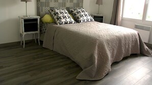 Une chambre à coucher avec un lit, deux tables de chevet, une tête de lit à motifs et une fenêtre avec des rideaux.