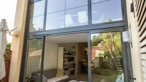 A modern house with large sliding glass doors leading to a living area with a sofa and a coffee table.