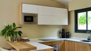 A modern kitchen with a wooden island, white cabinets, a built-in microwave, and a pendant light.