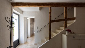 A staircase with a wooden beam structure, a white cabinet with a red flower, and a metal stand with a spiral design. - Farmhouse fully renovated in provence - Superb swimming pool 9m X 9m (Cavaillon)