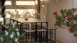 An outdoor patio with a wooden table and chairs, a stone wall, and a tiled roof. - Farmhouse fully renovated in provence - Superb swimming pool 9m X 9m (Cavaillon)