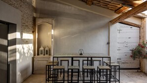A rustic kitchen with a wooden table and chairs, a cabinet, and a white door. - Farmhouse fully renovated in provence - Superb swimming pool 9m X 9m (Cavaillon)