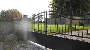 A gated entrance with a gravel path leading to a grassy area.