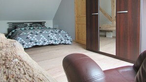 A bedroom with a bed, a wooden door, a wardrobe, and a chair.