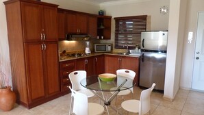 A compact kitchen with wooden cabinets, a glass dining table, and white chairs. - Ocean Front studio for 2, Cabarete (Cabarete)