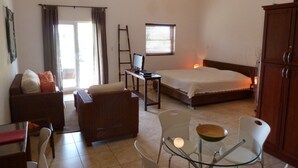 A bedroom with a bed, a desk with a computer, a sofa, and a dining area with chairs and a table. - Ocean Front studio for 2, Cabarete (Cabarete)