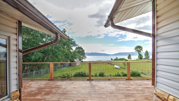 Una terraza de madera con vistas a un área verde y montañas a lo lejos.