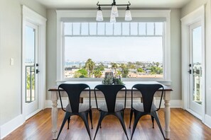 A dining area with a table and chairs, a large window with a city view, and a chandelier.