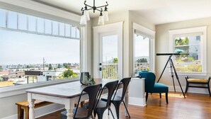 A spacious room with a large dining table, chairs, and a telescope.