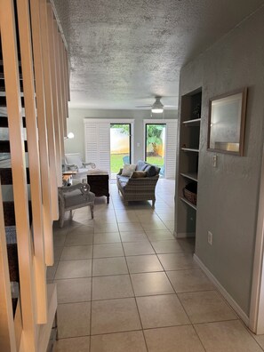 A spacious living area with a sofa, a chair, and a coffee table. There are sliding glass doors leading to a patio.
