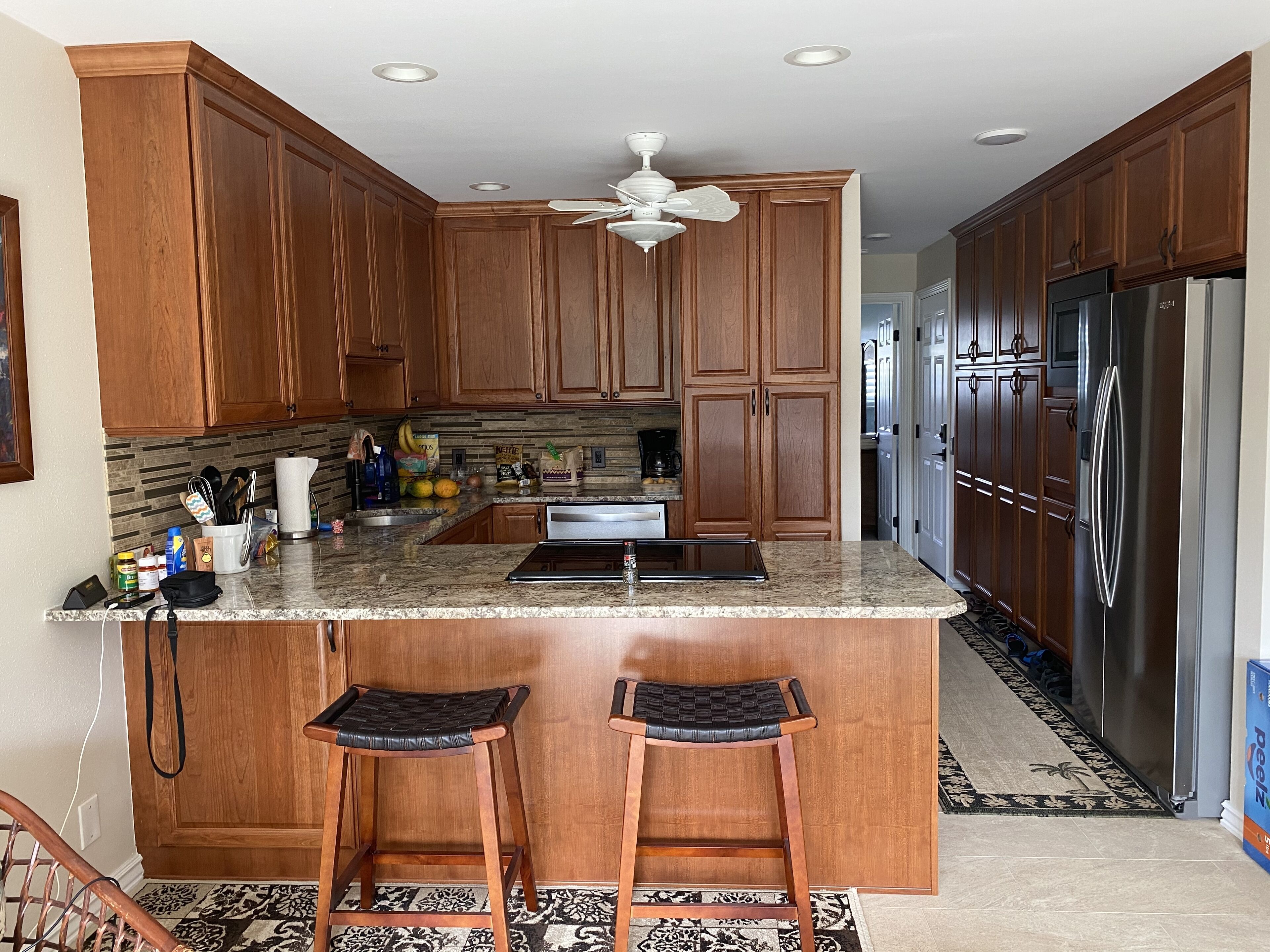 A kitchen with wooden cabinets, a granite countertop, a built-in stove, and a refrigerator.