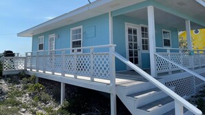 A two-story building with a white porch and a satellite dish. - Seaweed  Cottage   With Atlantic Ocean  View (exuma)