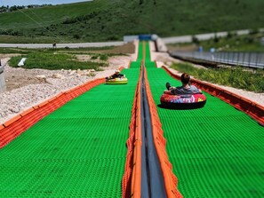 A person in a colorful inflatable tube sliding down a green, textured slide.