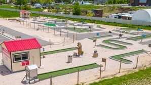 A zoo with a bear enclosure, green pathways, and a small red-roofed building.